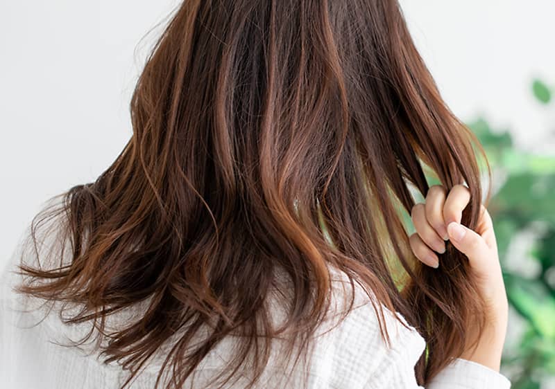 žena má ruku vo svojich dlhých vlasoch