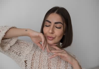 Žena má zatvorené oči a usmieva sa s dokonale nalíčenými perami