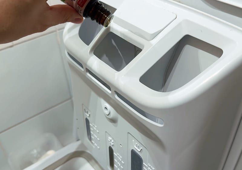 kvapkanie éterického oleja do dávkovača pracieho prášku v práčke