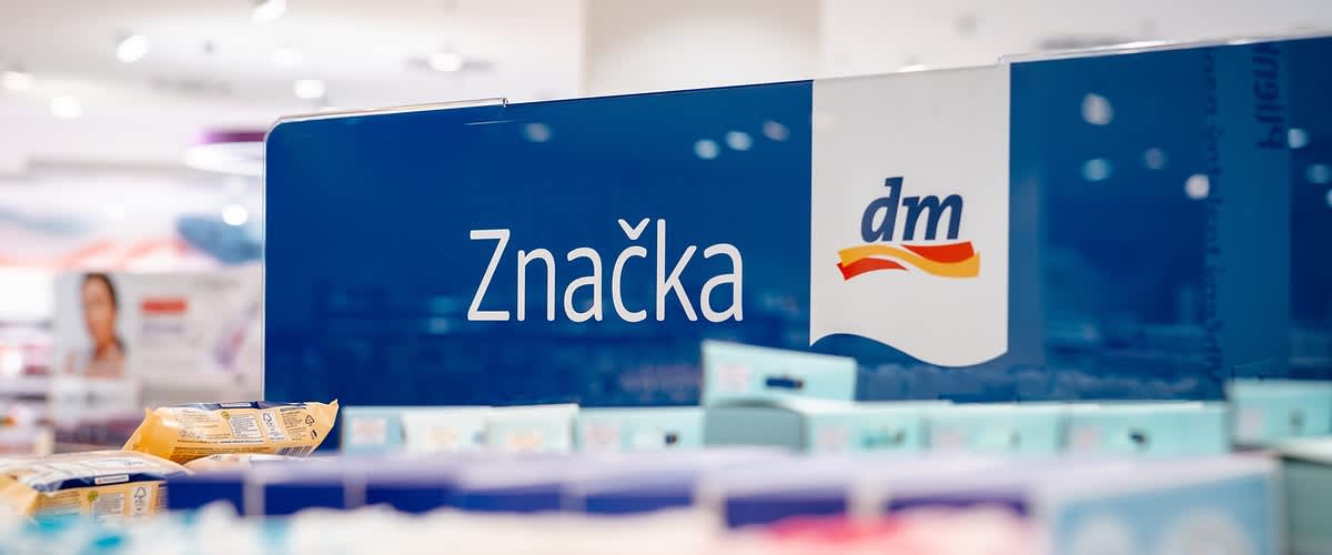 Tabula s textom "Značka dm" nad regálom v predajni dm