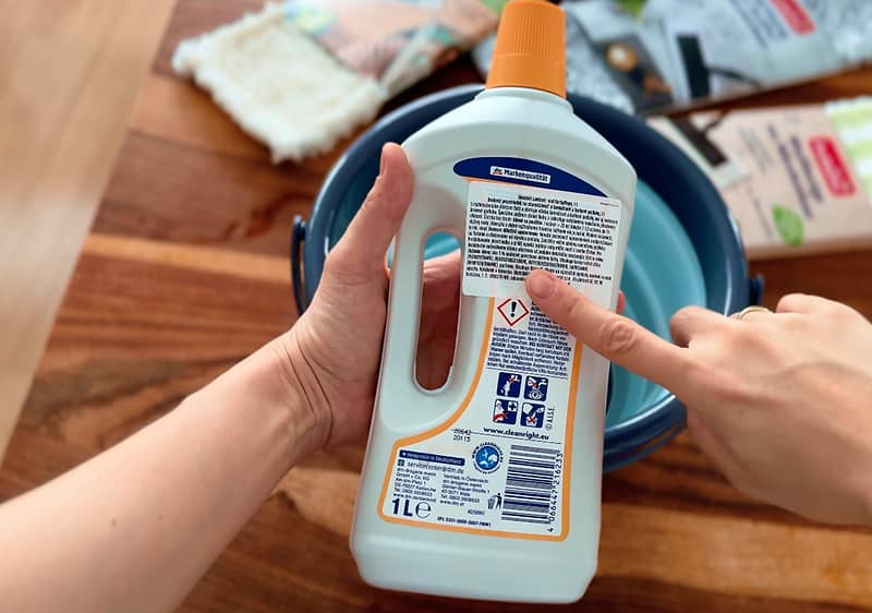 Prst ukazujúci na etiketu čistiaceho prostriedku na podlahu