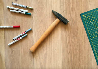 Kladivo a fixky položené na stole