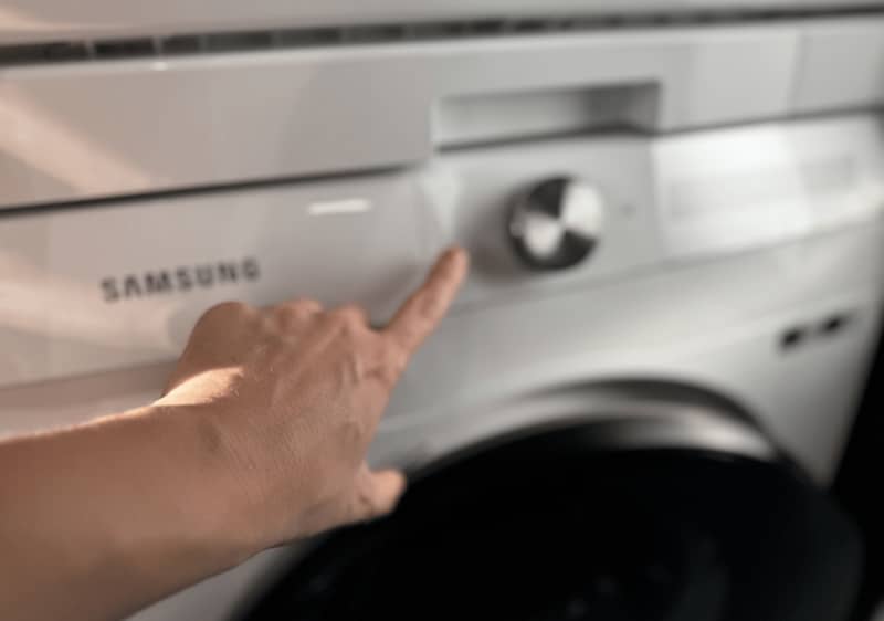 Ruka nastavuje ovládací panel práčky Samsung