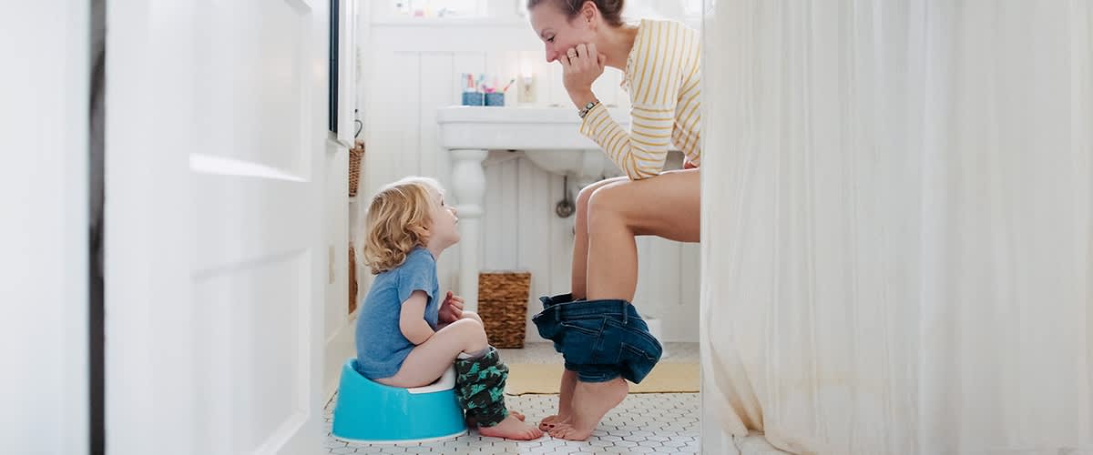 Dieťa sedí na nočníku a oproti jeho matka na toalete