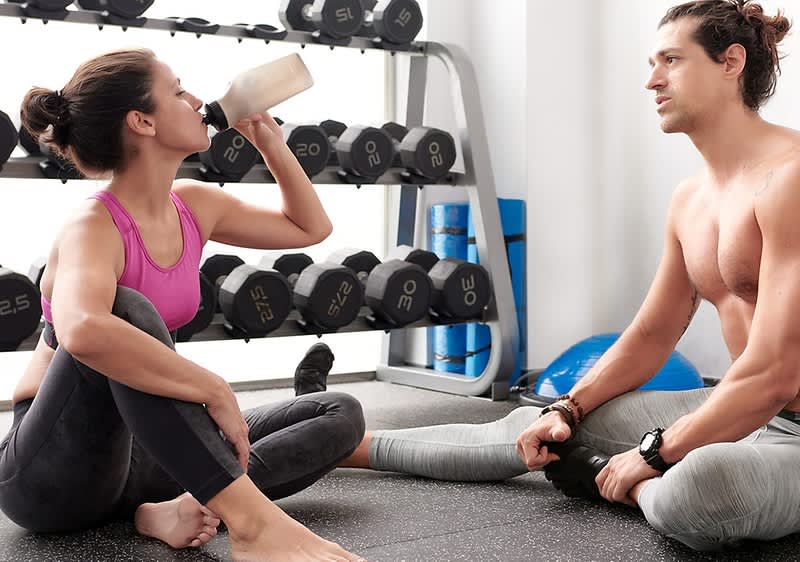 Žena pijúca proteínový shake zo športovej fľaše