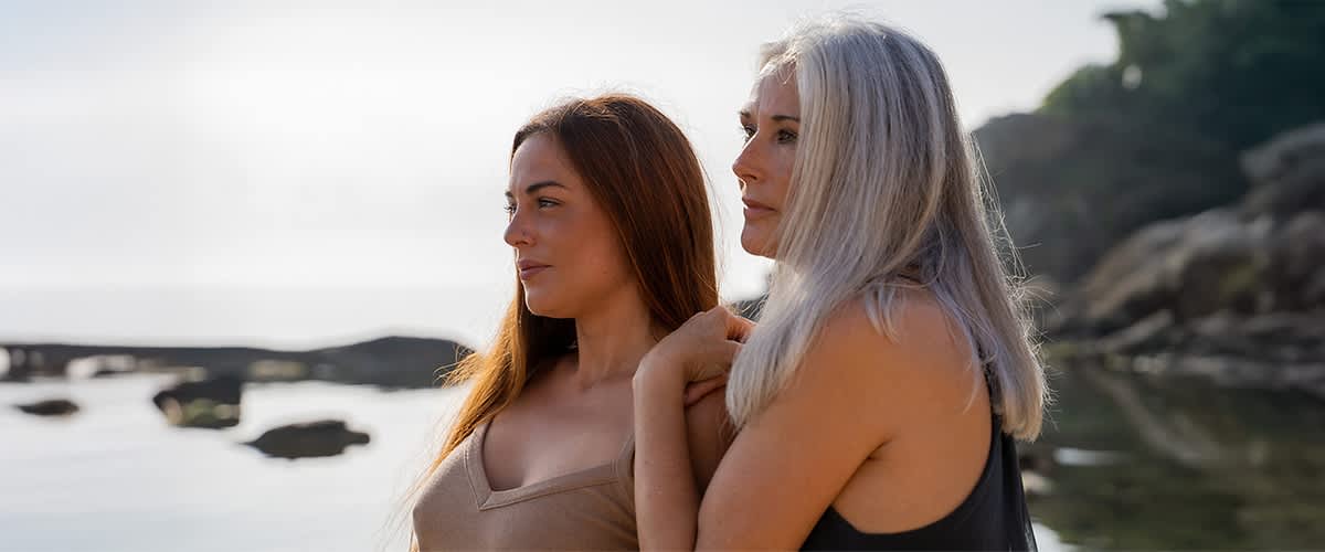 Dve ženy rôzneho veku stojace na pláži