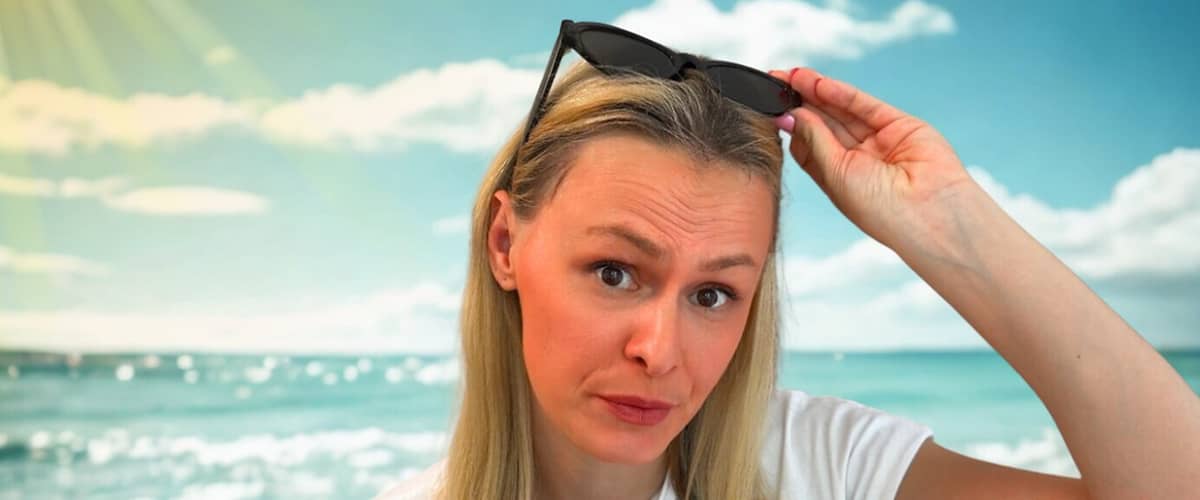 Žena na pláži so slnečnými okuliarmi na hlave