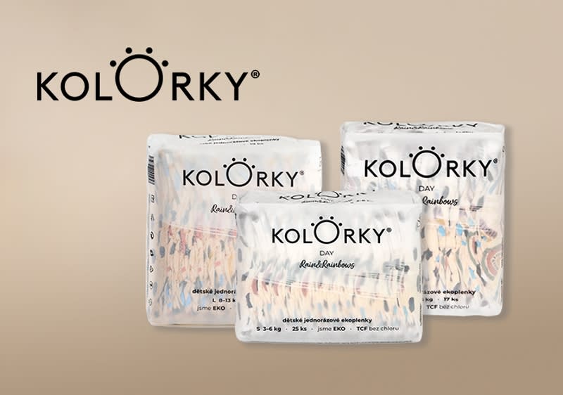 Dieťa v plienke a balenia plienok značky Kolorky na béžovom pozadí