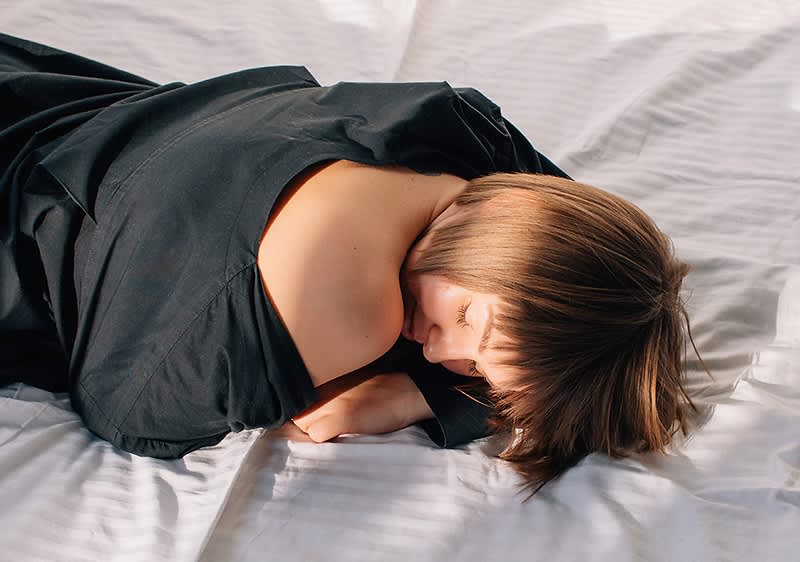 Žena ležiaca na bielych obliečkach