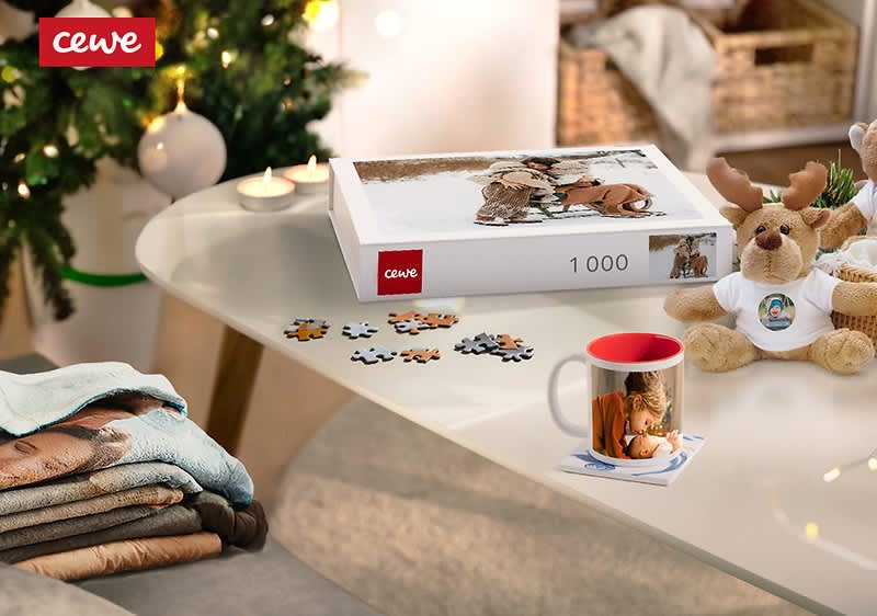 Vianočný stôl s puzzle, hrnčekom, plyšovým sobom a zloženými dekami