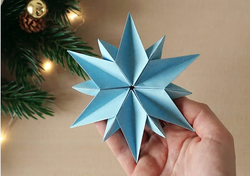 Modrá origami hviezda z papiera v ruke