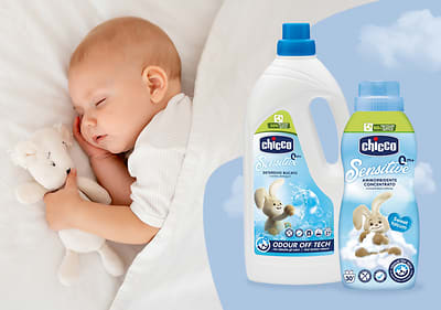 Dieťa s plyšovým medvedíkom, vedľa sú dva pracie prostriedky značky Chicco Sensitive