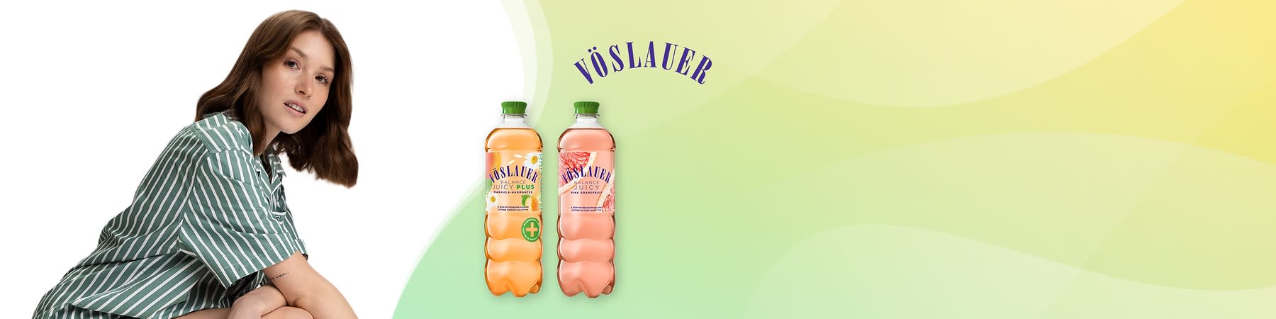 Mladá žena pozerá do kamery vedľa dvoch fliaš Voslauer nápoja na svetlom zelenom pozadí