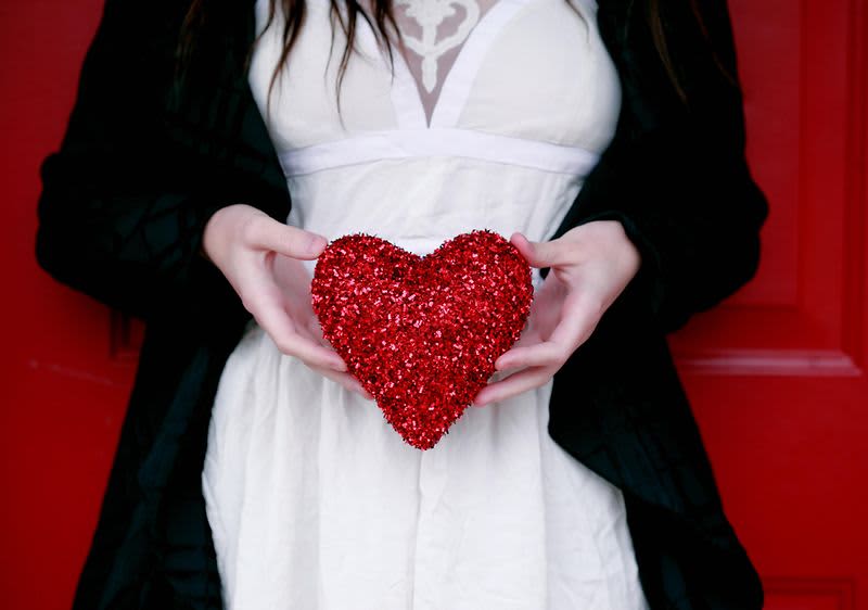 Žena drží v rukách vlentínske srdce.