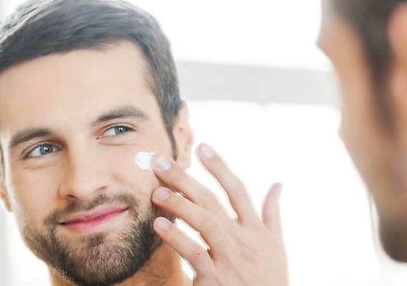 muž, ktorý si krémuje tvár