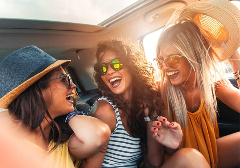 Trojica dievčat v aute s klobúkmi.