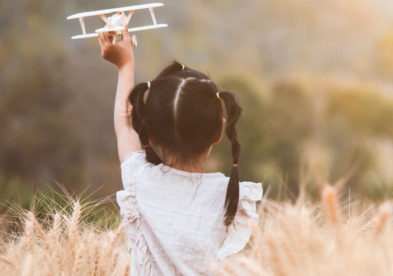 dieťa v poli s lietadlom v ruke