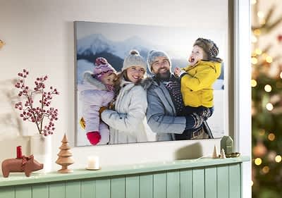 Rodinná fotografia na stene, zimné oblečenie, zasnežené hory v pozadí, vianočná výzdoba v miestnosti.