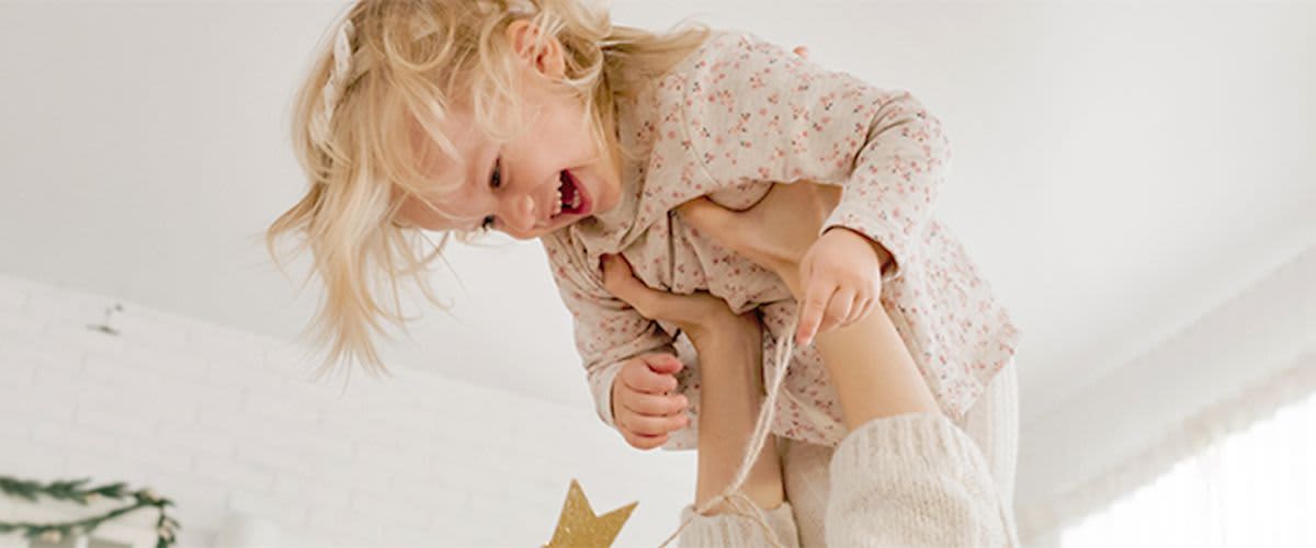 šťastné dieťa v náručí rodiča pred stromčekom