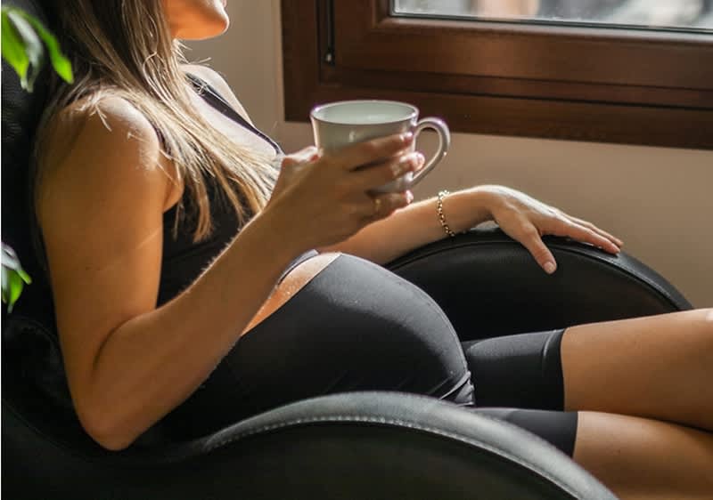 Schwanger mit Tasse Tee auf Bauch