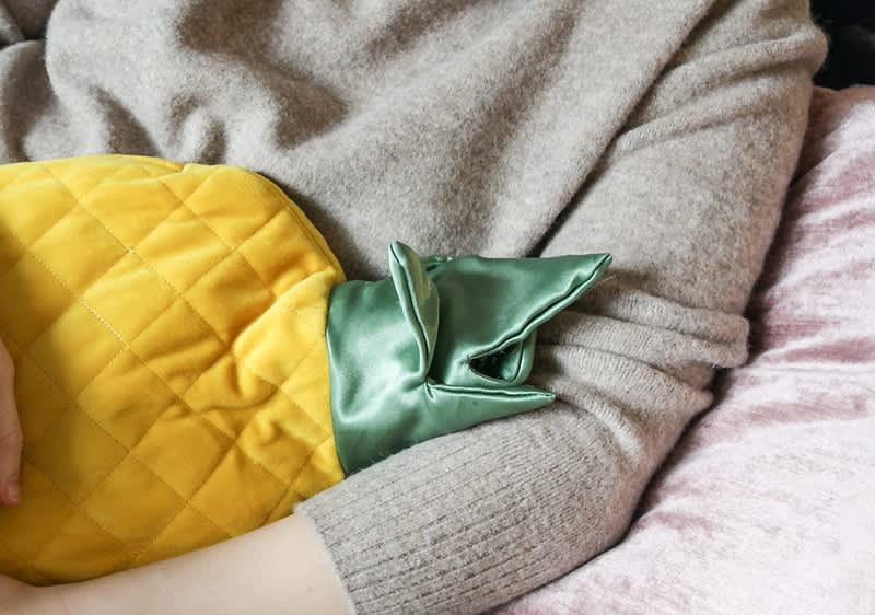 Ženska sedi s termoforjem na trbuhu