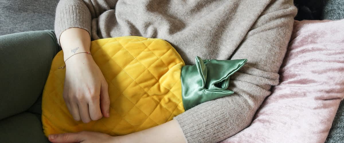 Ženska sedi s termoforom na trbuhu