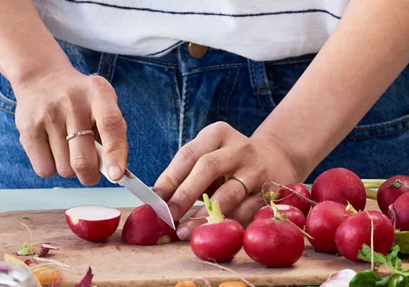 Oseba v kuhinji pripravlja zelenjavo na kuhinjskem pultu