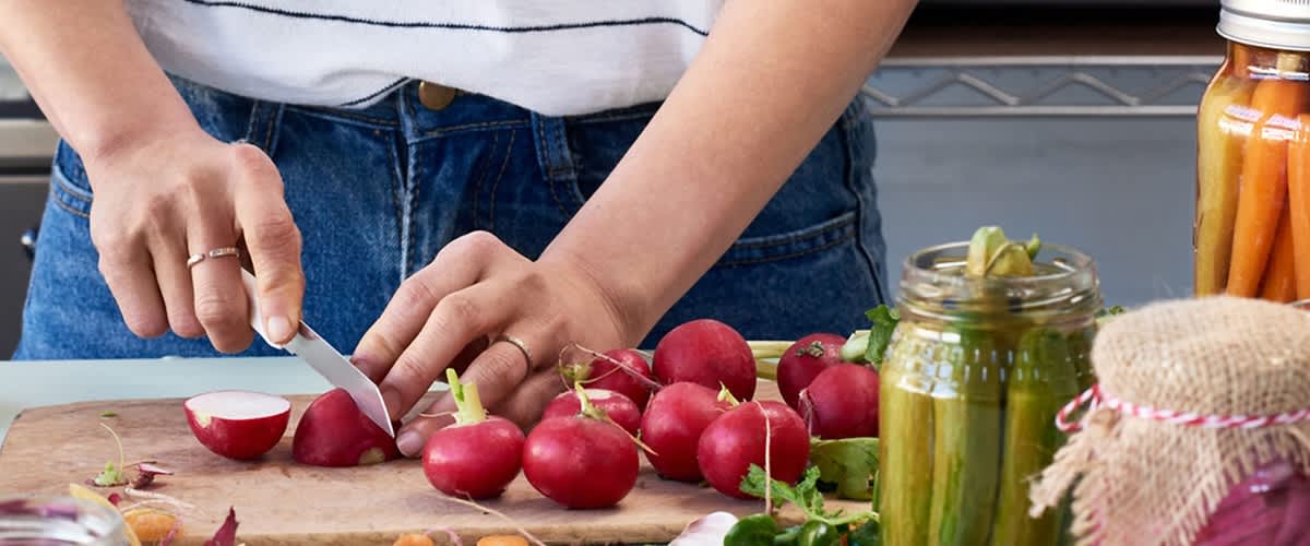 Oseba v kuhinji pripravlja zelenjavo na kuhinjskem pultu