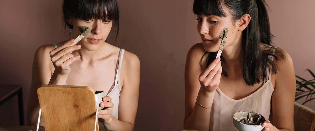 Ženska z masko za obraz in skodelico v roki