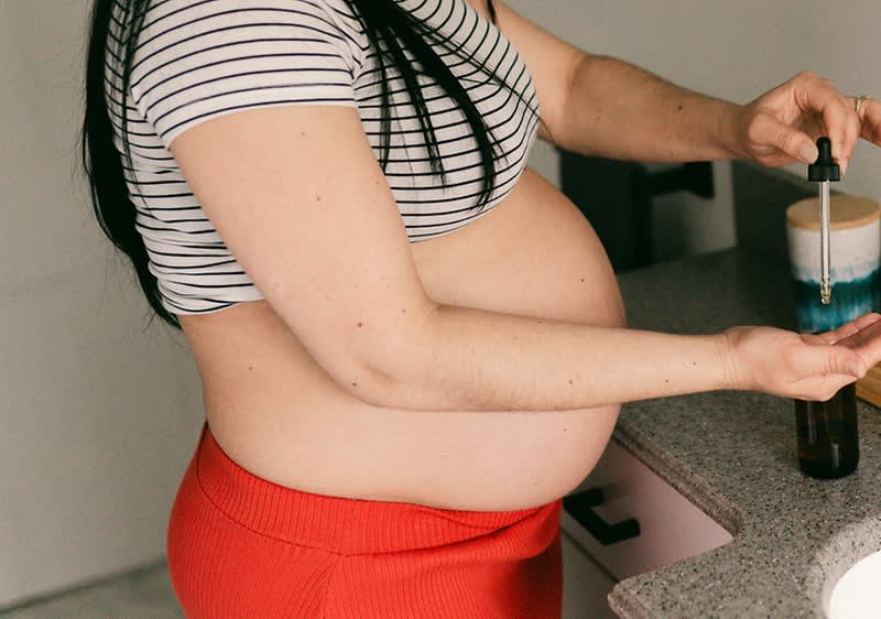 Nosečnica v rdečem krilu uporablja kapljice na roki