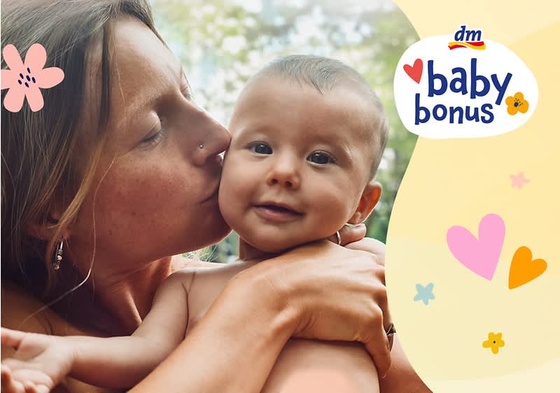 Mama drži dojenčka z napisom baby bonus in cvetličnimi motivi