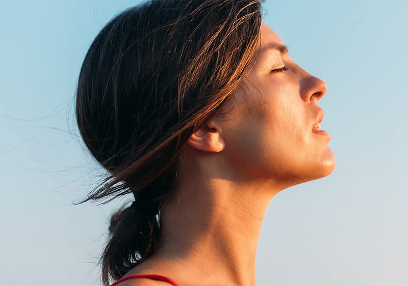 Ženska z rjavimi lasmi oblečena v rdečo obleko na prostem pod modrim nebom