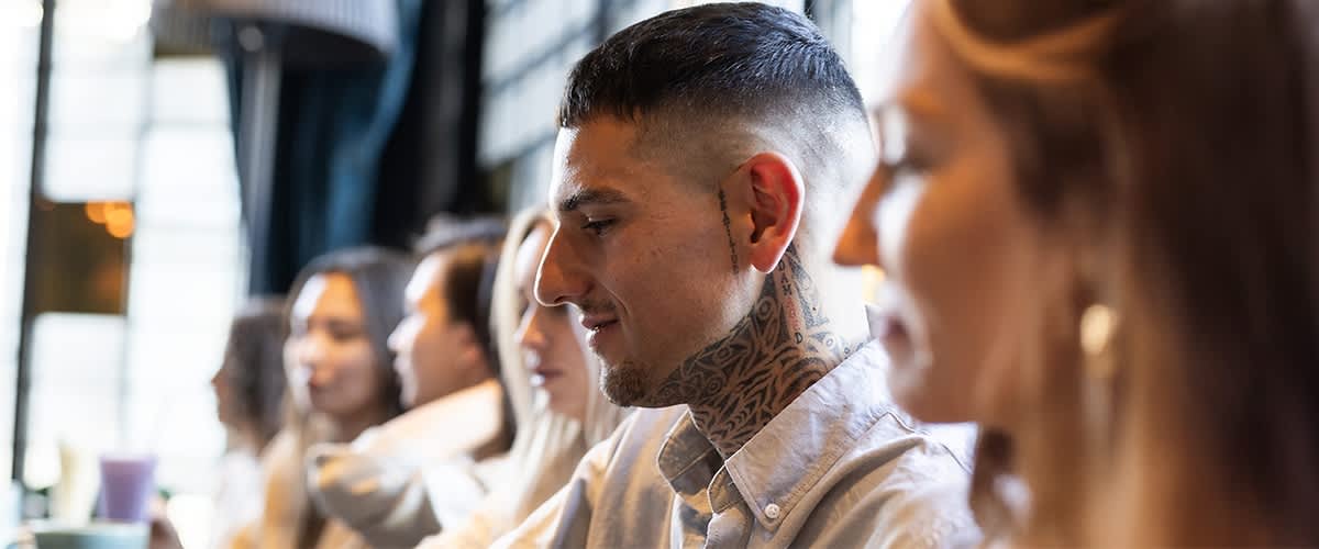 Alt-Text Moški s tetovažo na vratu v restavraciji