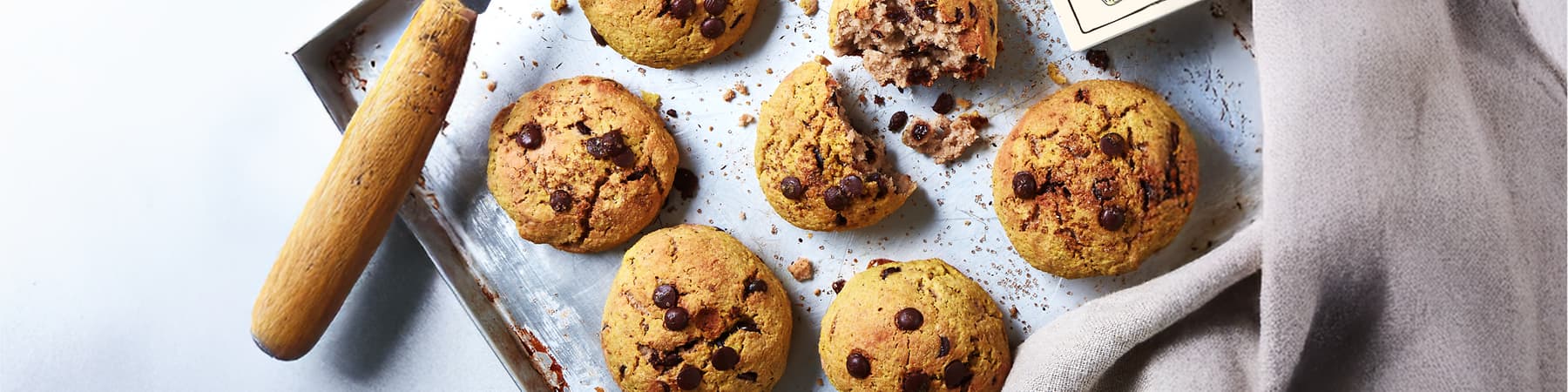 Piškoti s čokoladnimi koščki na pekaču, eden je delno zlomljen