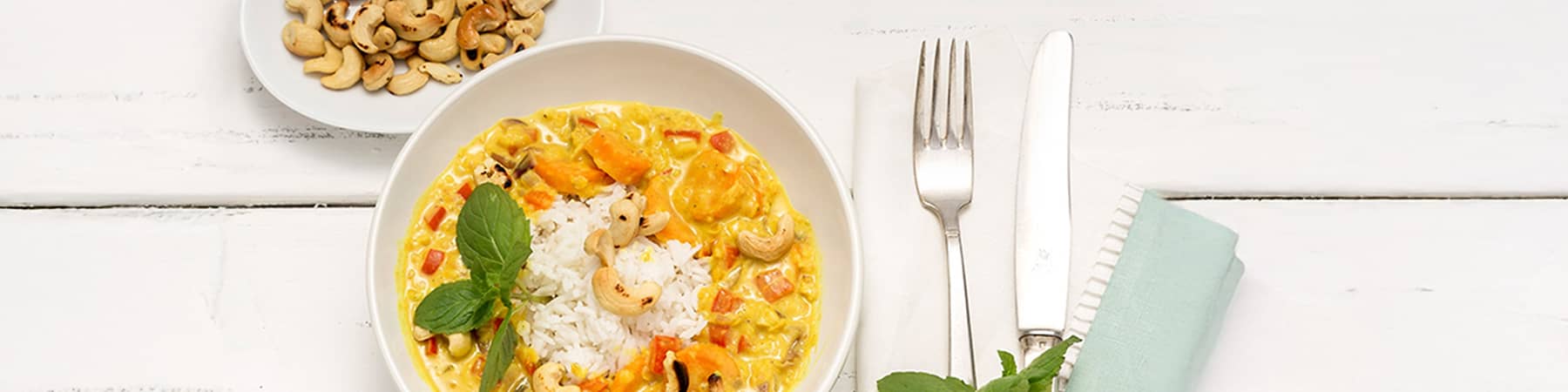 Indijska jed z rižem, indijskimi oreščki in meto na beli mizi