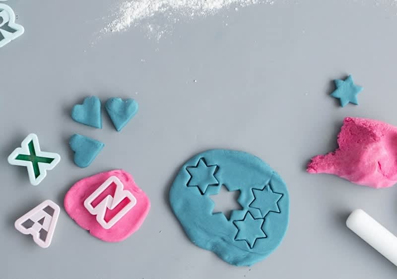 Alt-Text Modelčki za plastelin v obliki črk in zvezd na sivi podlagi