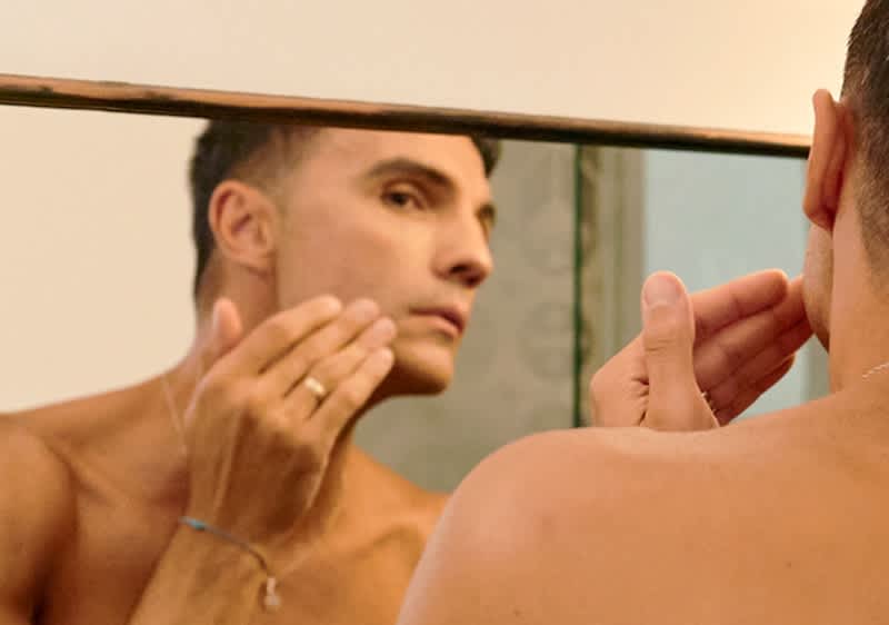 Moški pred ogledalom z zapestnico na roki