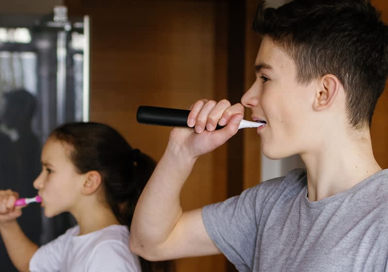 Otroka si umivata zobe z električnimi zobnimi ščetkami