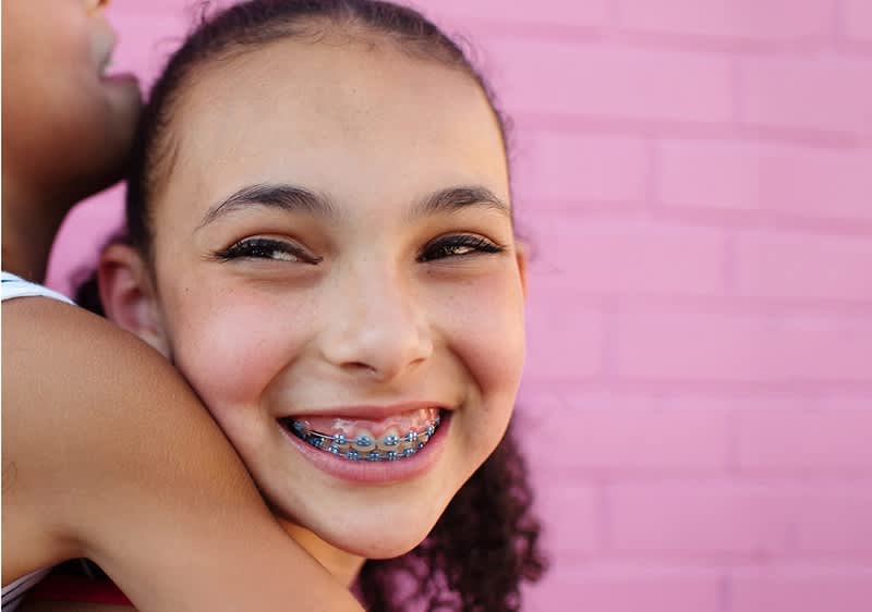 Alt-Text: Otrok z kodrastimi lasmi ob roza steni