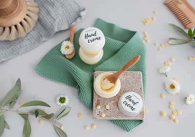 Alt-Text Naravna krema za roke na zelenem prtičku z leseno žlico in cvetovi