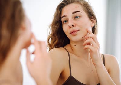 Alt-Text: Ženska z dolgimi kodrastimi lasmi v ogledalu, zamegljen obraz