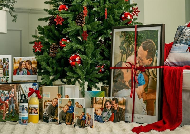 Alt-Text Božično drevo z okraski in darili, vključno s koledarji in fotografijami družine