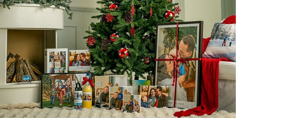 Alt-Text Božično drevo z okraski in darili, vključno s koledarji in fotografijami družine