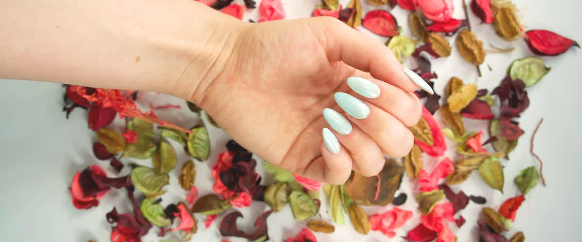 Svetlo modra manikura z roko na cvetličnem ozadju.