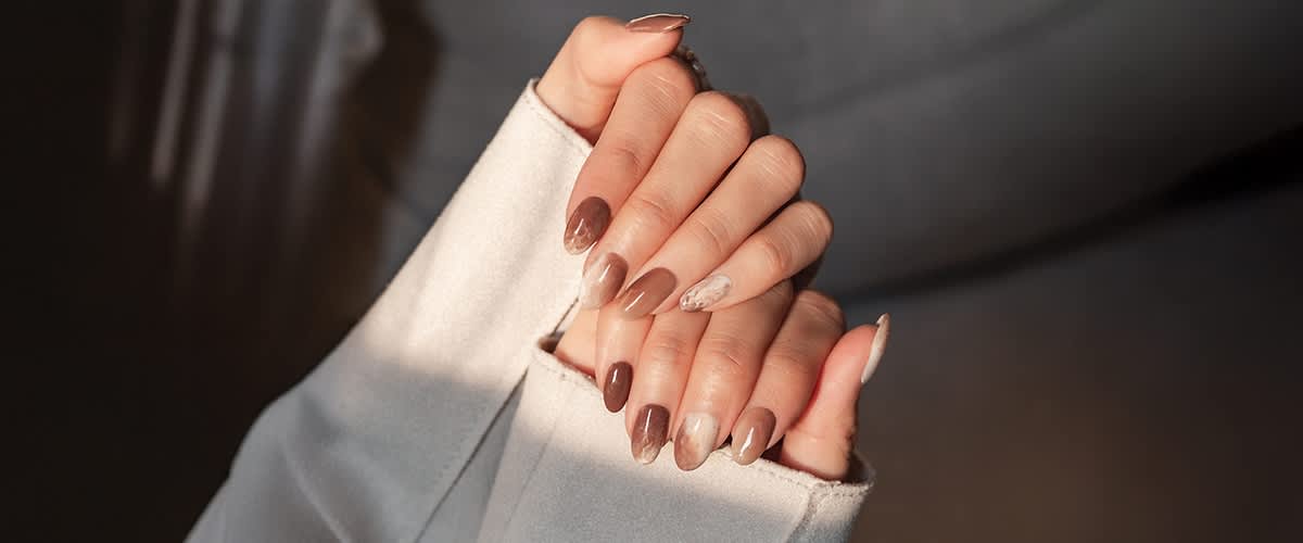 Roke z elegantnim nude in rjavim gel nohtnim dizajnom s marmornimi vzorci