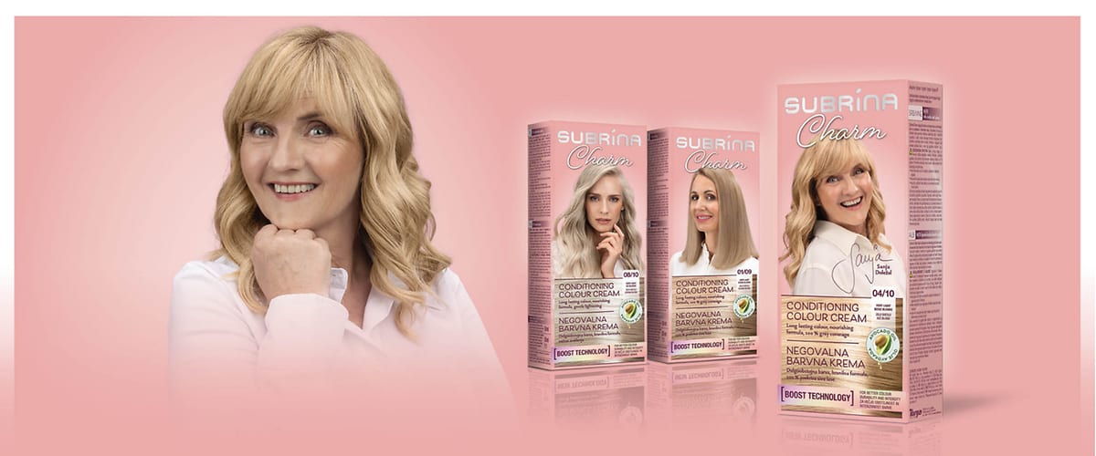 Ženska z blond lasmi, nasmejana s podprtko brade in škatle barv za lase znamke Subrina Charm, embalaže z ženskami in logotip