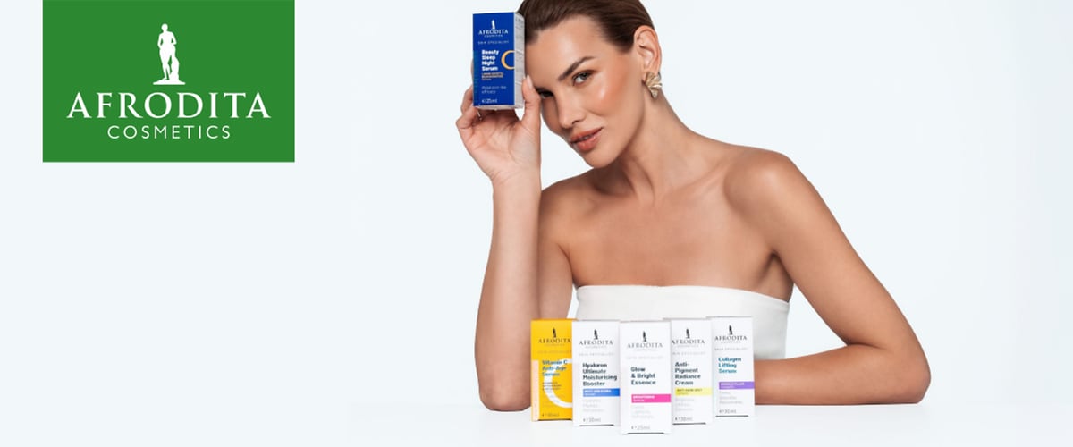 Ženska drži kozmetični izdelek Afrodita Cosmetics ob policah z različnimi serumi in logotipom Afrodita Cosmetics