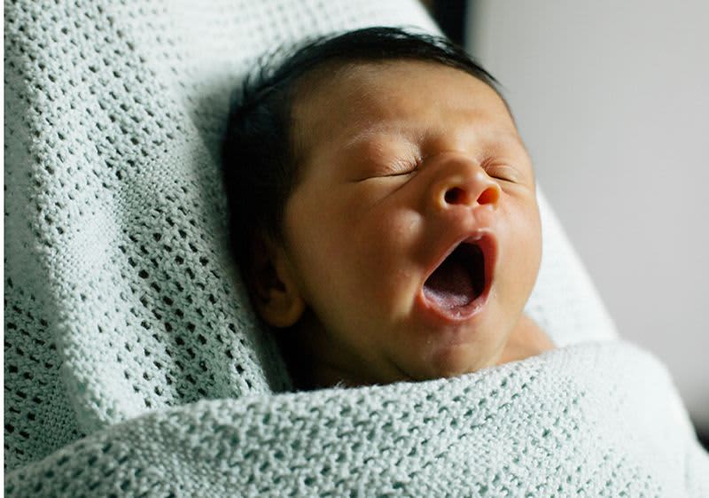 Eingewickeltes Baby gähnt