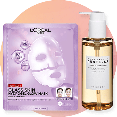 Eine lila Verpackung von L'Oréal Revitalift Glass Skin Feuchtigkeits-Fluid neben einem Essence Bright Eyes Produkt in Orange.