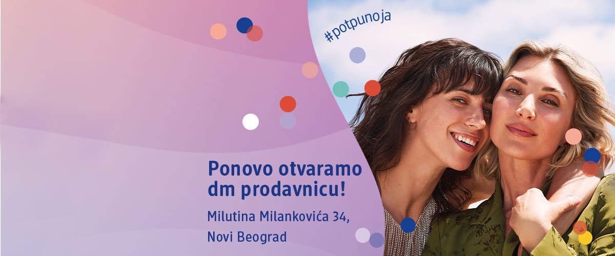 Slika koja prikazuje dve nasmejane žene u zagrljaju ispred promotivnog banera dm prodavnice